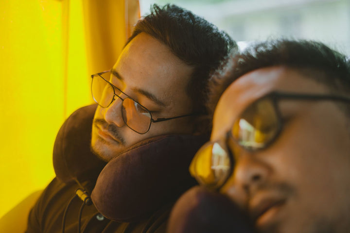 Travelers sleeping on a bus with neck pillows