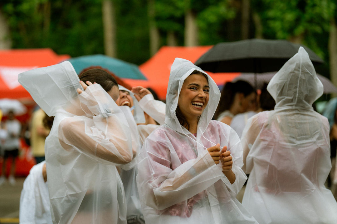 Friends laughing in clear rain ponchos at an outdoor event
